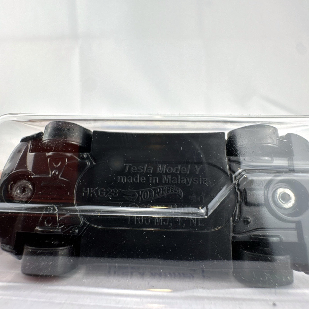 Hot Wheels 1:64 scale diecast Tesla Model Y SUV in dark gray metallic inside factory sealed card packaging.