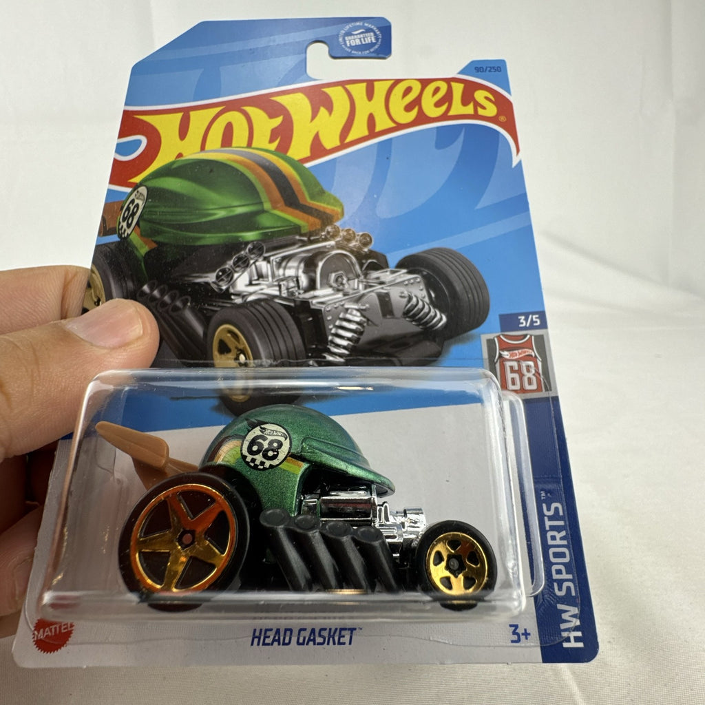 Sealed 2022 Hot Wheels Head Gasket 1:64 scale diecast car in metallic green baseball helmet style on original card.