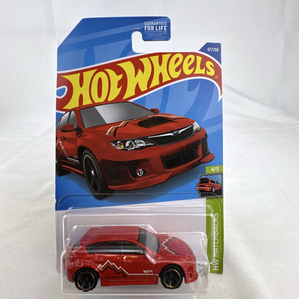 Hot Wheels 1:64 scale Subaru WRX STI diecast car in red sealed on HW Hatchbacks card packaging.