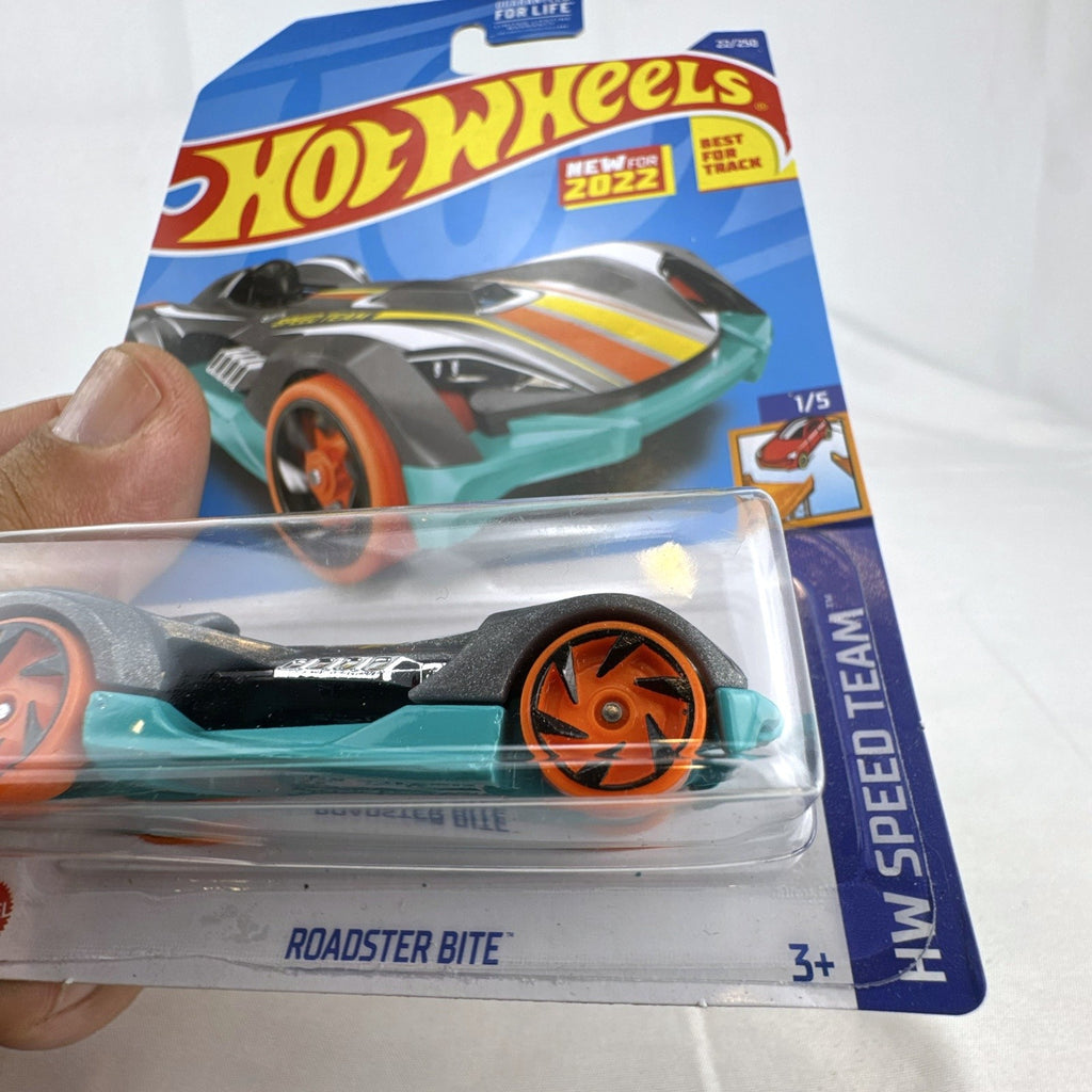 Hot Wheels Roadster Bite 1:64 scale diecast car sealed on card in satin gray with orange wheels.
