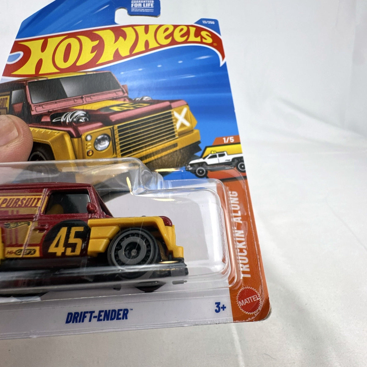 Hot Wheels 1:64 scale Drift-Ender Land Rover Defender diecast truck in dark red and gold, factory sealed on card.
