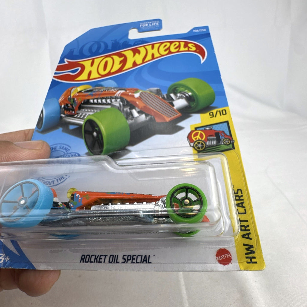 Hot Wheels 1:64 scale Rocket Oil Special diecast car in orange paint splatter from the HW Art Cars series on original card
