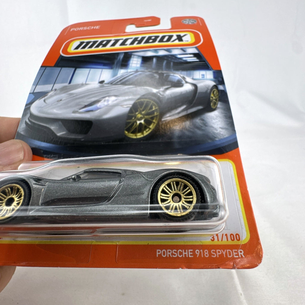 Matchbox 1:64 scale Porsche 918 Spyder diecast car in dark metallic grey with gold rims sealed on original card
