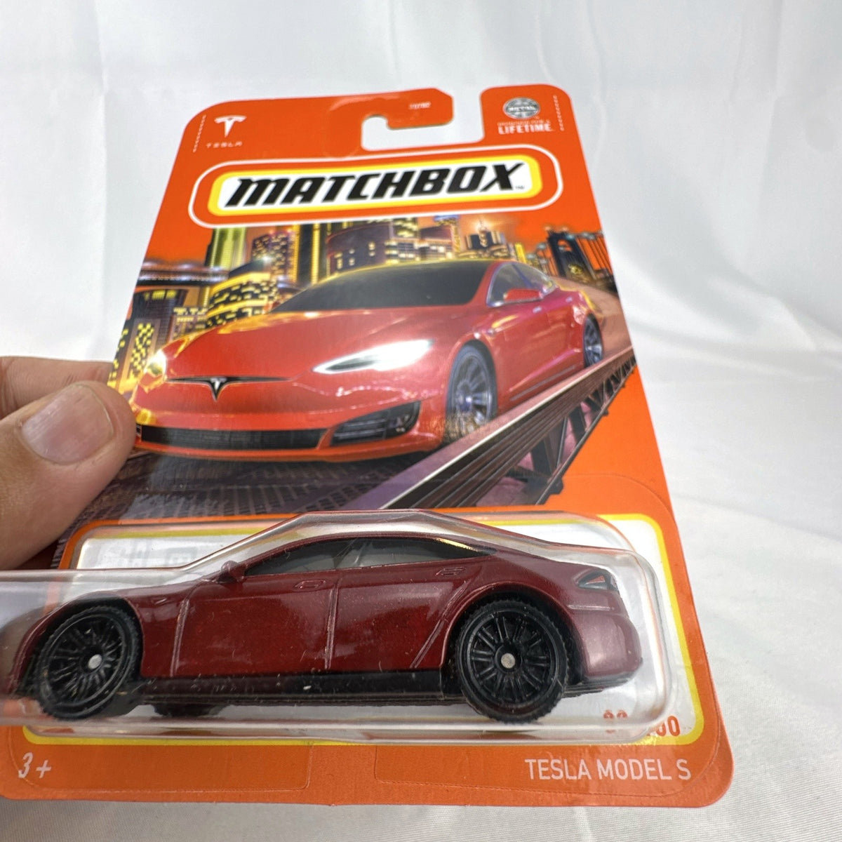 Matchbox 1:64 scale Tesla Model S diecast car in metallic dark red, factory sealed on original cardback