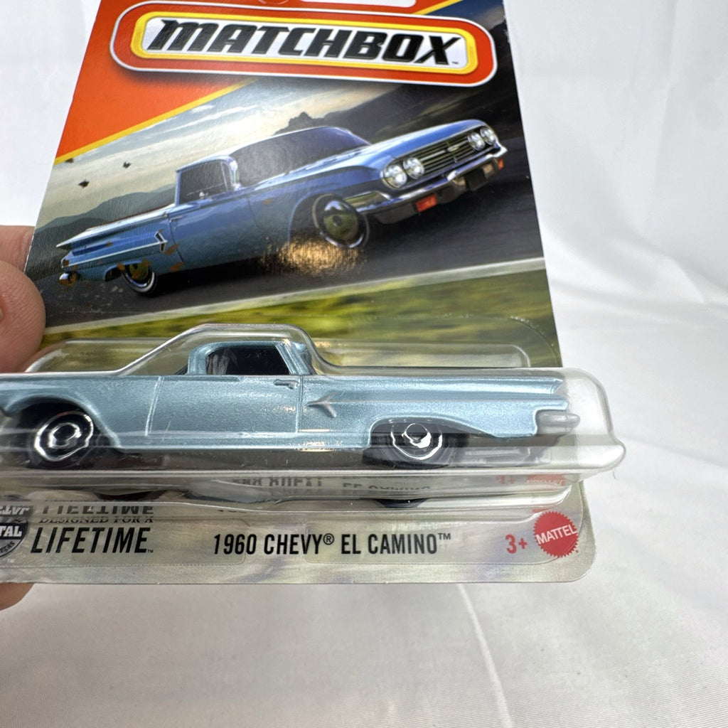 Matchbox 1:64 scale diecast 1960 Chevrolet El Camino pickup truck in metallic light blue unopened blister card packaging.