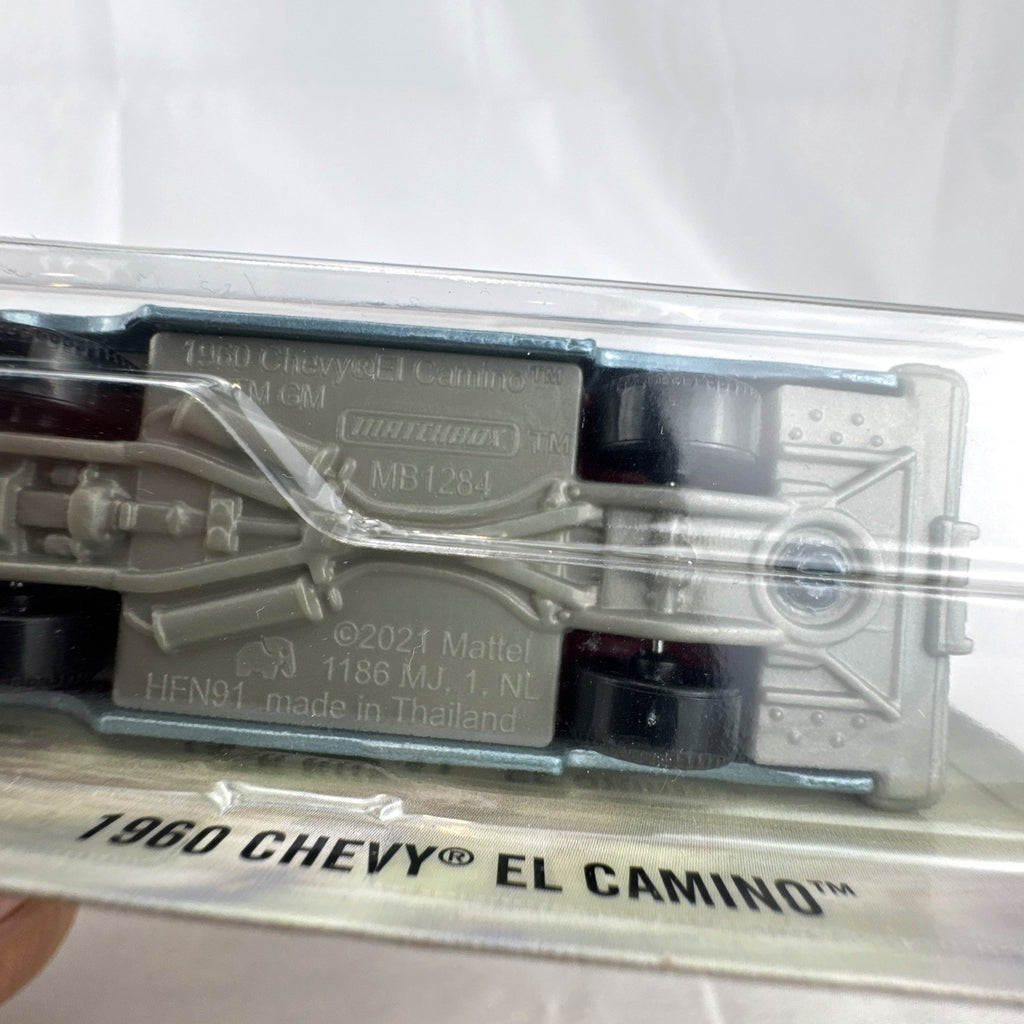 Matchbox 1:64 scale diecast 1960 Chevrolet El Camino pickup truck in metallic light blue unopened blister card packaging.