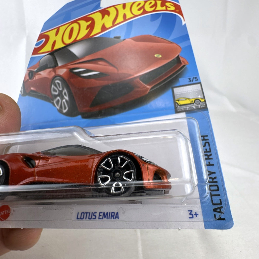 Hot Wheels Factory Fresh 1:64 scale Lotus Emira diecast car in metallic red sealed in original blister pack.