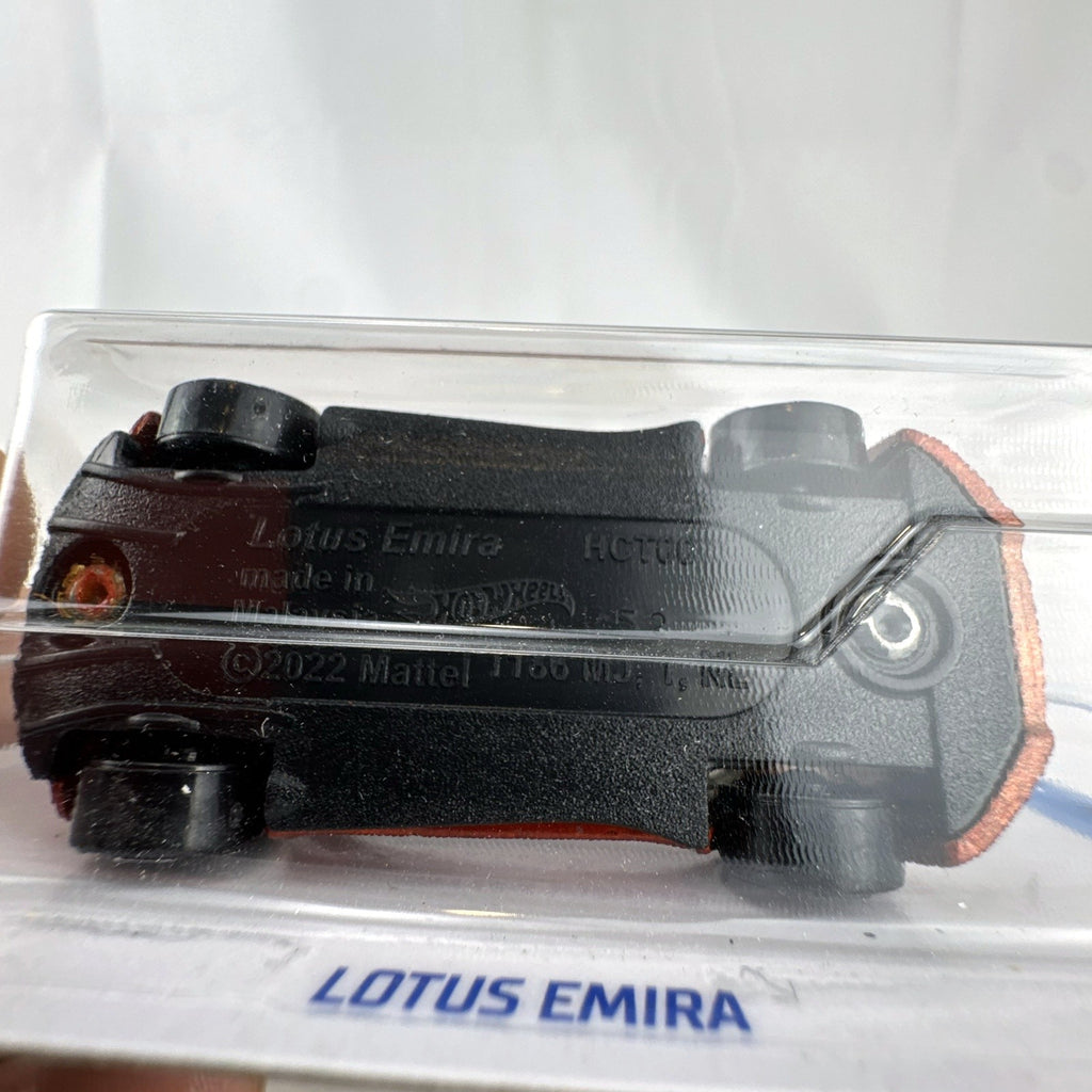 Hot Wheels Factory Fresh 1:64 scale Lotus Emira diecast car in metallic red sealed in original blister pack.