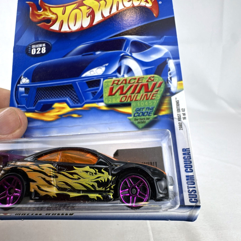 Unopened 2002 Hot Wheels Custom Cougar 1:64 scale diecast car in black with orange dragon flame graphics and purple wheels