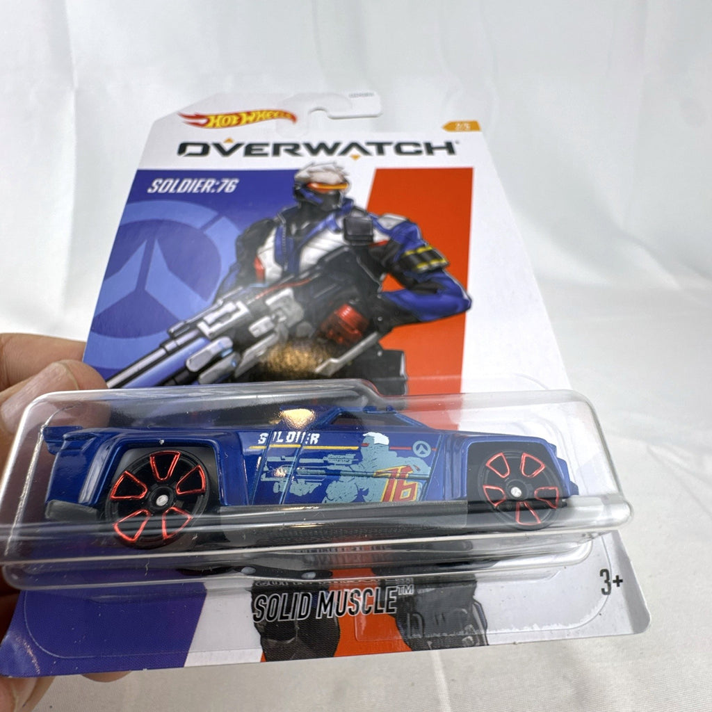 Hot Wheels 1:64 scale Solid Muscle diecast car featuring Blizzard Overwatch hero Soldier: 76 artwork in factory sealed card.