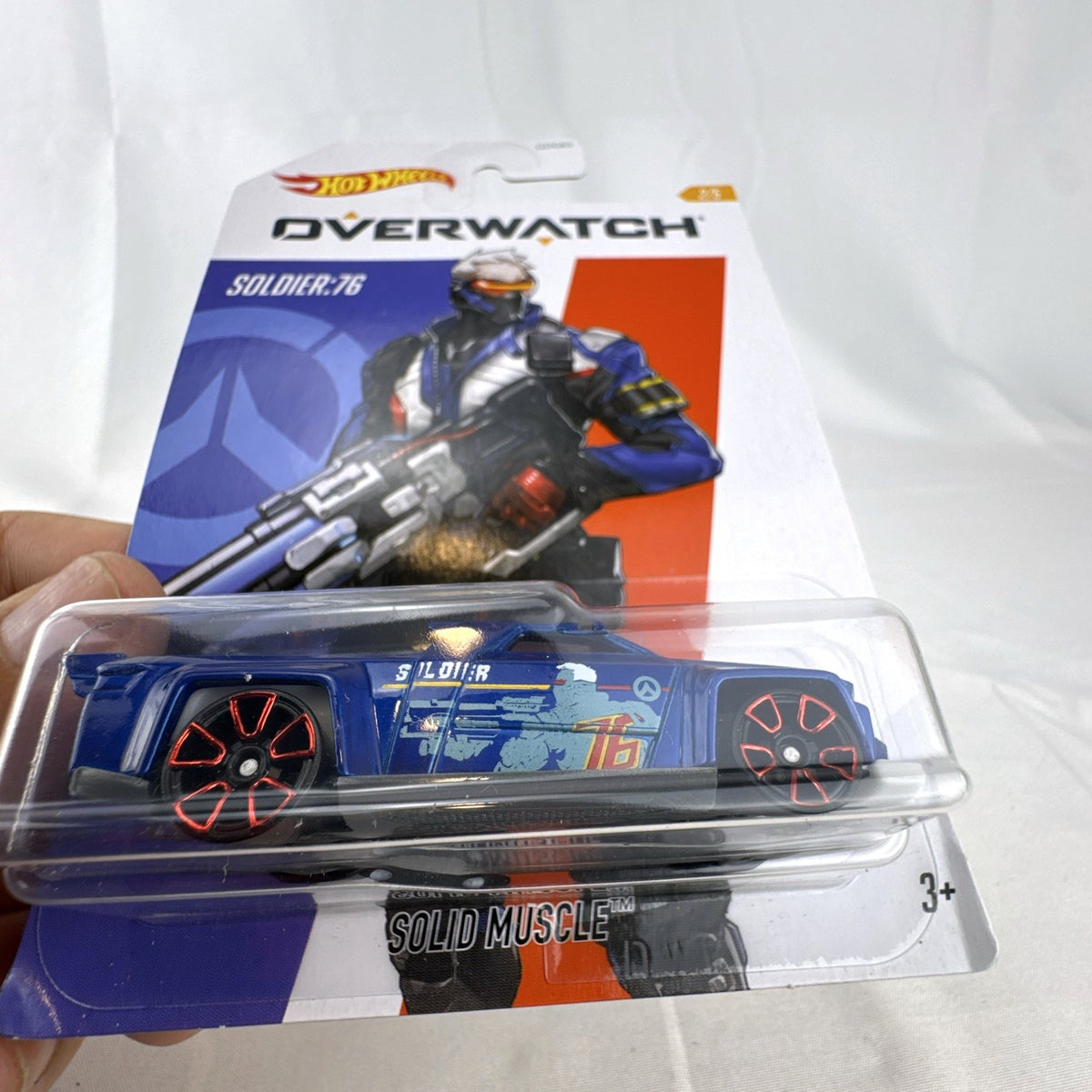 Hot Wheels 1:64 scale Solid Muscle diecast car featuring Blizzard Overwatch hero Soldier: 76 artwork in factory sealed card.