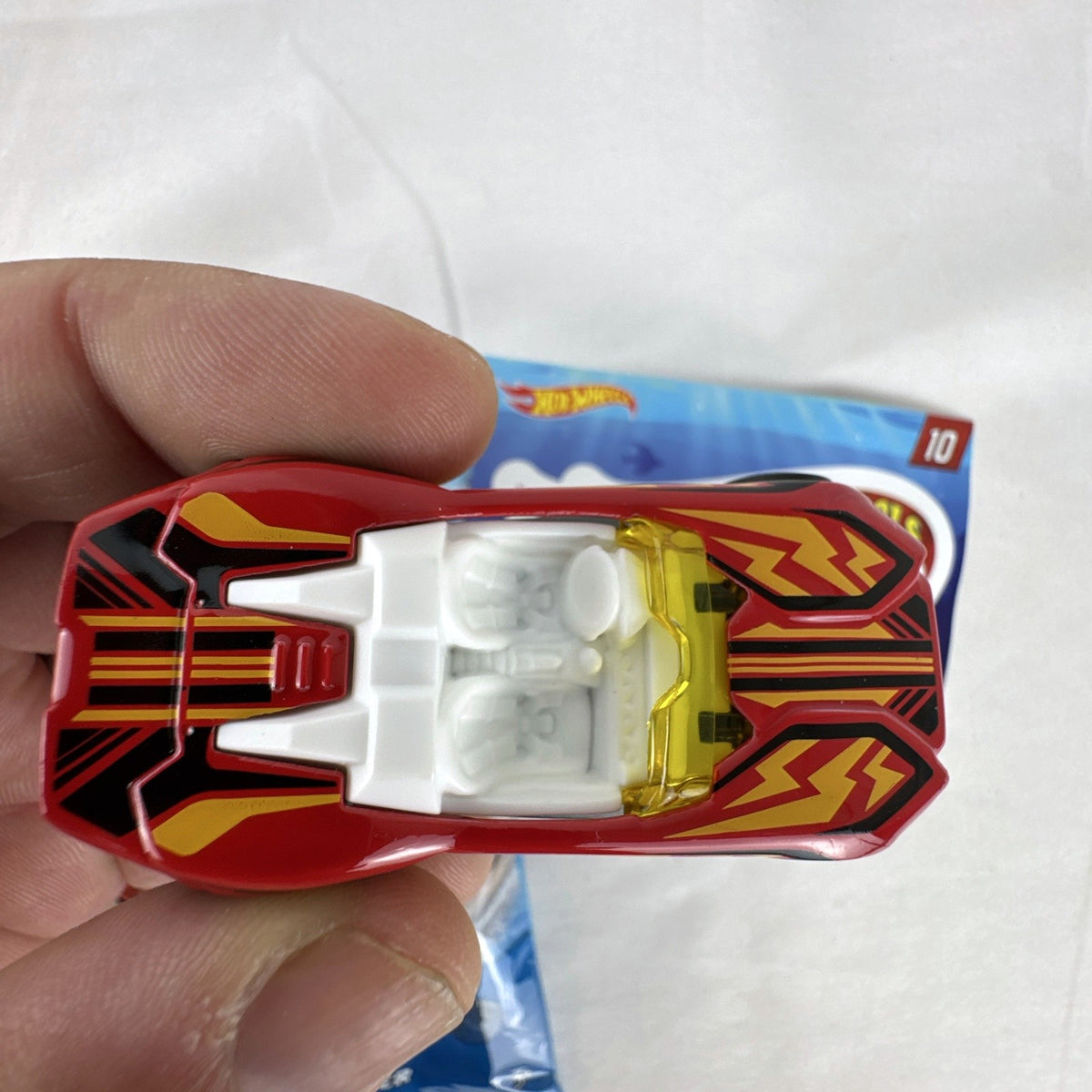 Red Hot Wheels Carbonic 1:64 scale diecast car from Mystery Models Series 2 with yellow graphics and opened foil pouch.