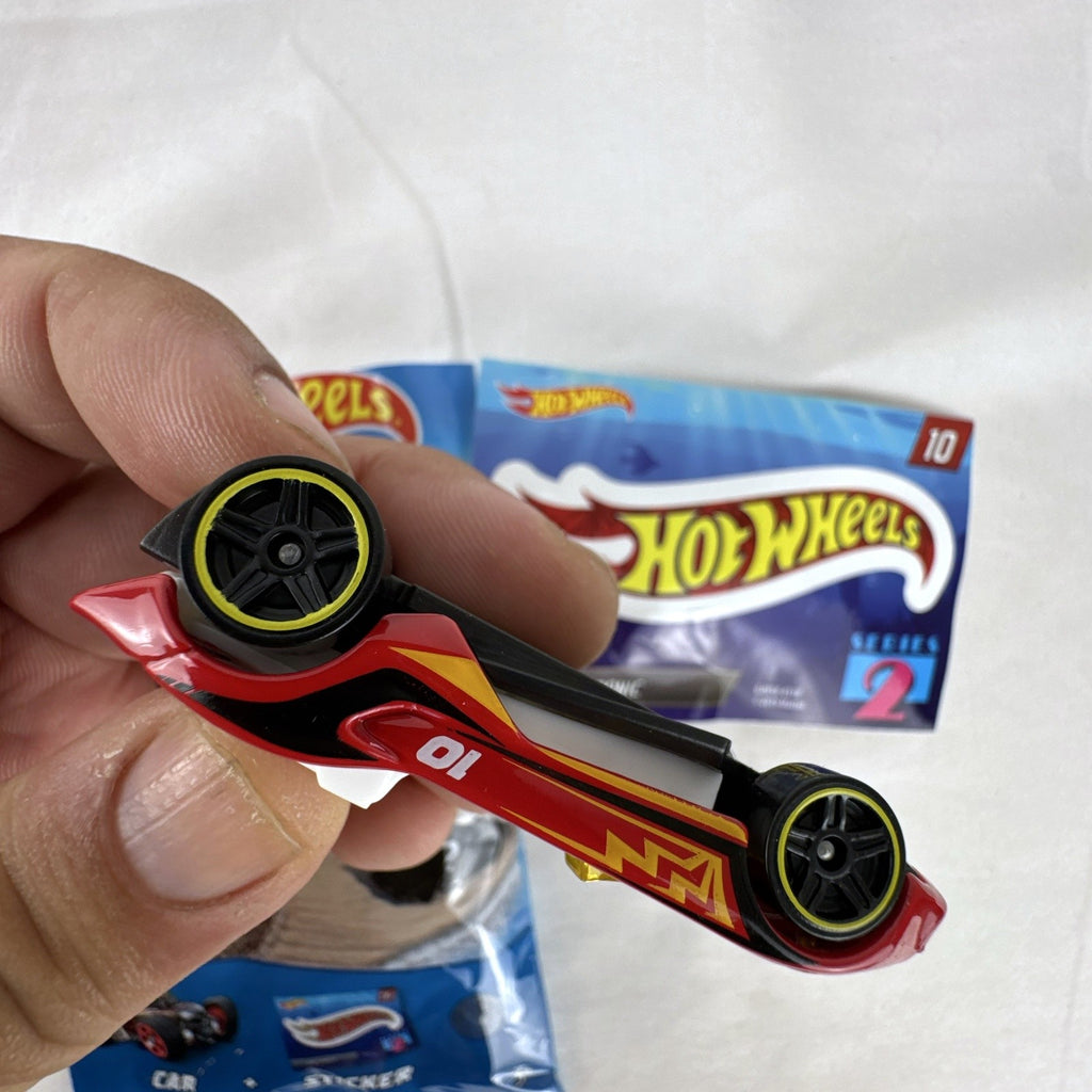 Red Hot Wheels Carbonic 1:64 scale diecast car from Mystery Models Series 2 with yellow graphics and opened foil pouch.