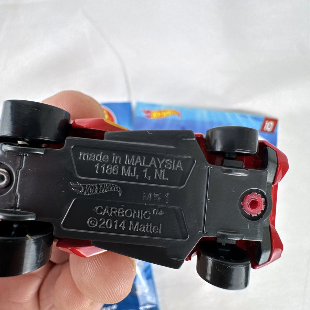 Red Hot Wheels Carbonic 1:64 scale diecast car from Mystery Models Series 2 with yellow graphics and opened foil pouch.