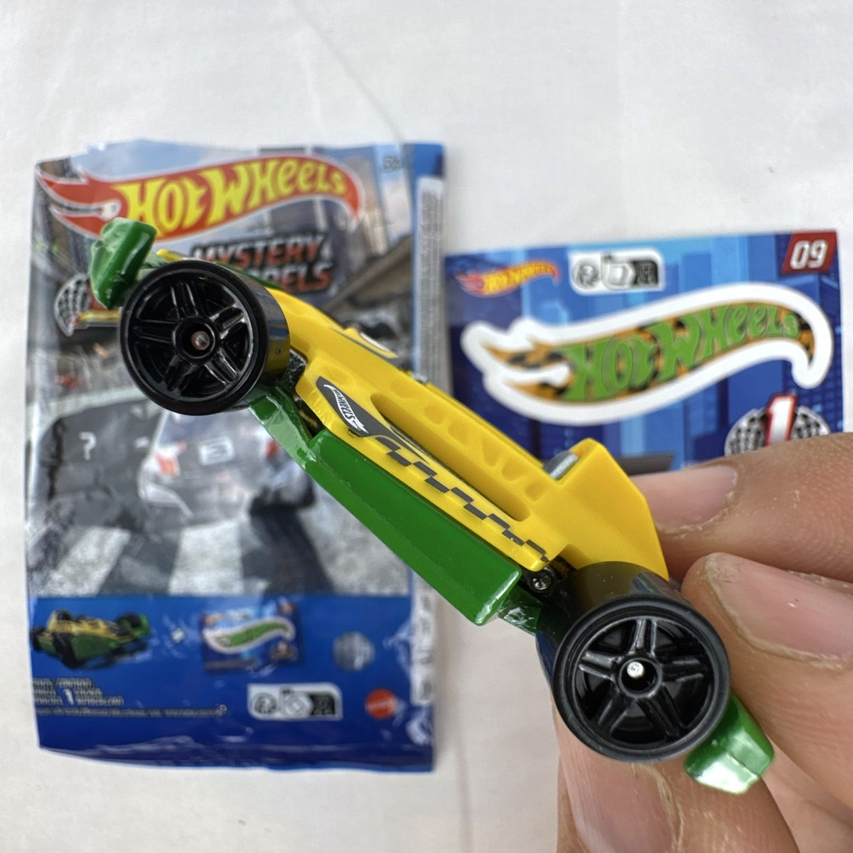 Yellow and green Hot Wheels Arrow Dynamic #09 Mystery Models 1:64 scale diecast car with original sticker card.