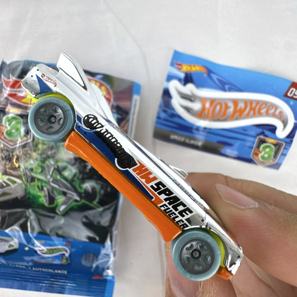 Hot Wheels Speed Slayer 1:64 scale diecast car in chrome with orange base, lime green canopy, foil bag, and sticker.