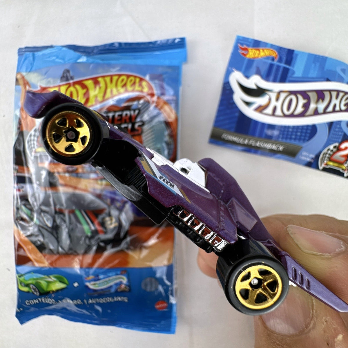 Hot Wheels Formula Flashback 1:64 scale purple diecast racer with gold wheels and matching sticker.