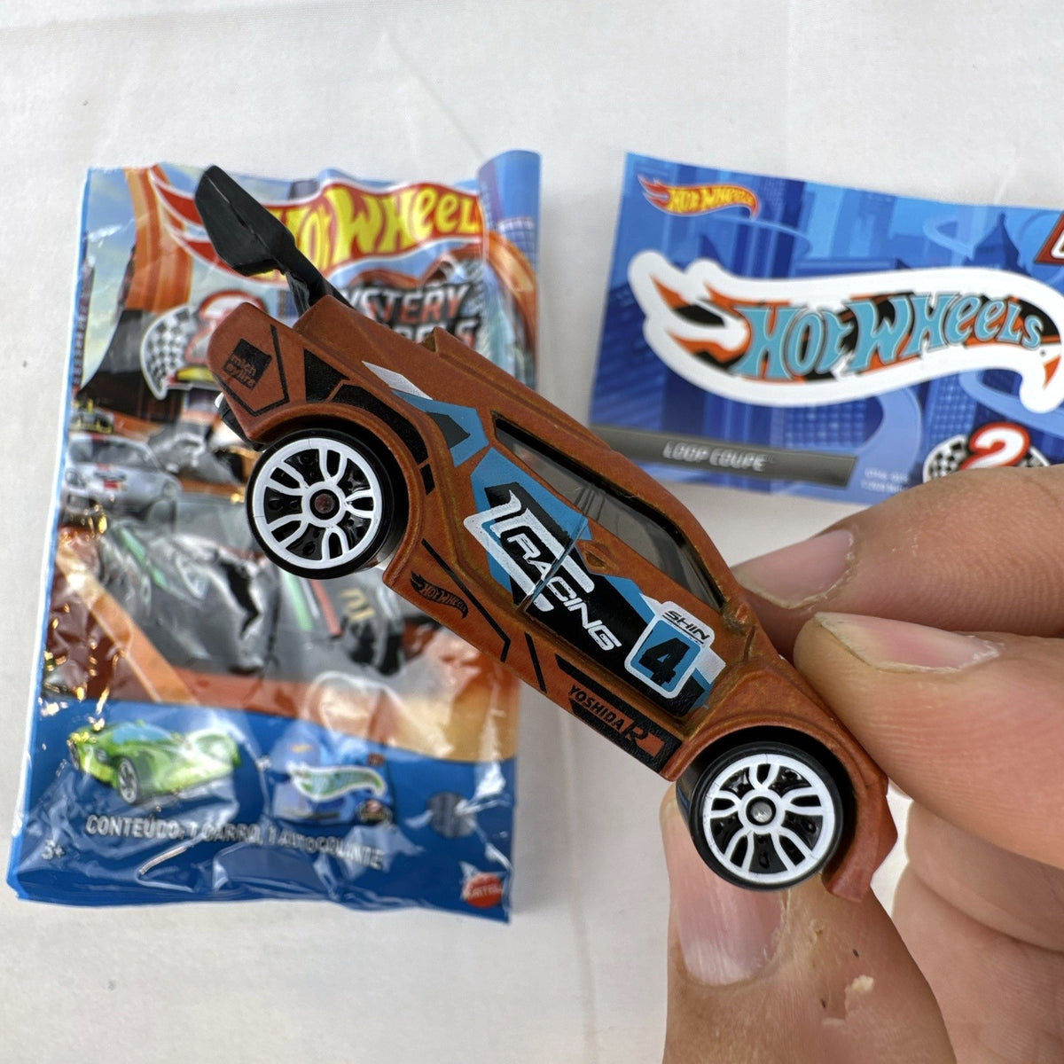 Hot Wheels 1:64 scale Loop Coupe diecast car in satin brown with HW Racing graphics and original foil packaging.