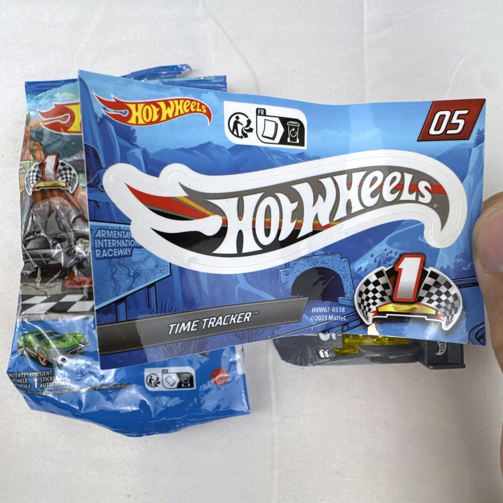 Dark gray Hot Wheels Time Tracker diecast car 1:64 scale with yellow wheels and mystery models sticker sheet.