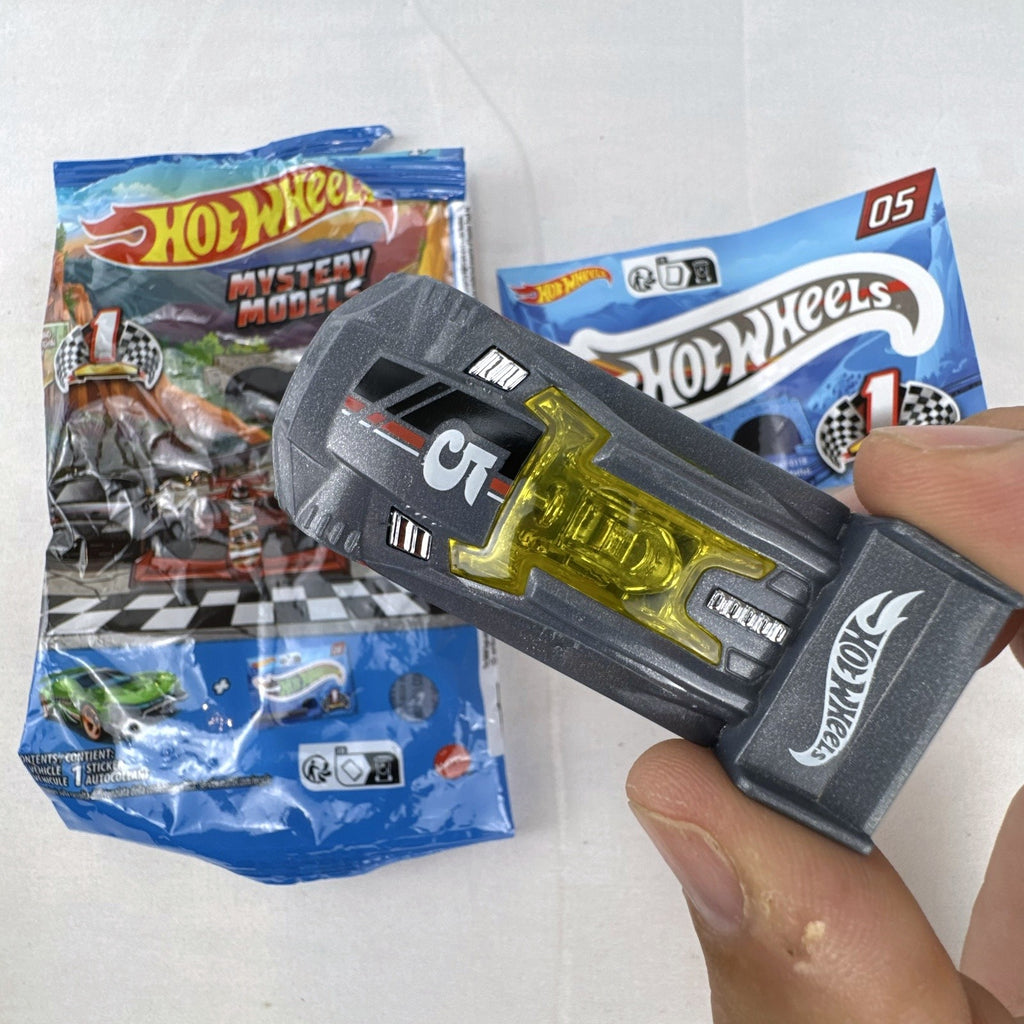 Dark gray Hot Wheels Time Tracker diecast car 1:64 scale with yellow wheels and mystery models sticker sheet.