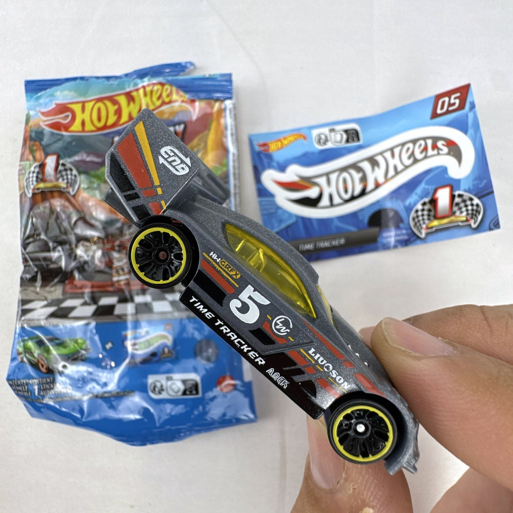 Dark gray Hot Wheels Time Tracker diecast car 1:64 scale with yellow wheels and mystery models sticker sheet.