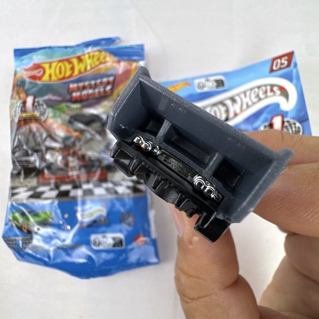 Dark gray Hot Wheels Time Tracker diecast car 1:64 scale with yellow wheels and mystery models sticker sheet.