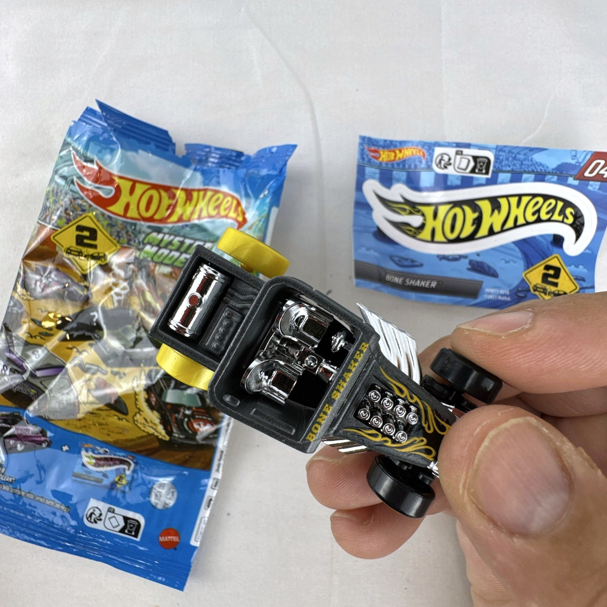 Hot Wheels 1:64 scale satin dark gray Bone Shaker mystery model diecast car with original mystery pouch and sticker