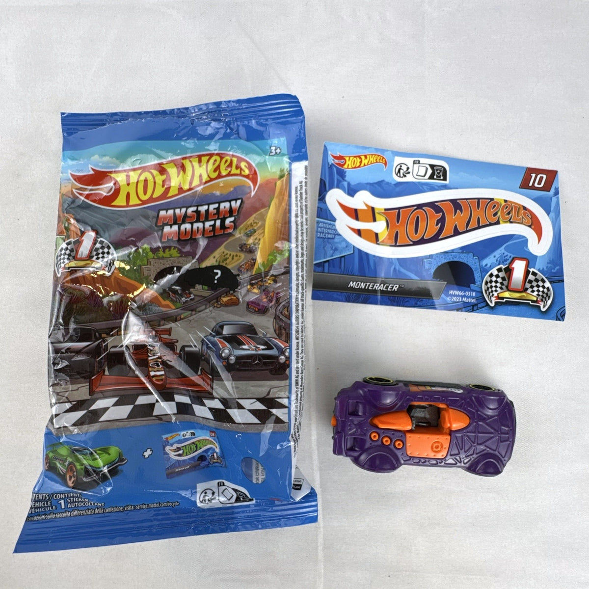 Hot Wheels 1:64 scale Monteracer diecast car in purple and orange from Mystery Models Series 1 with original bag and sticker.