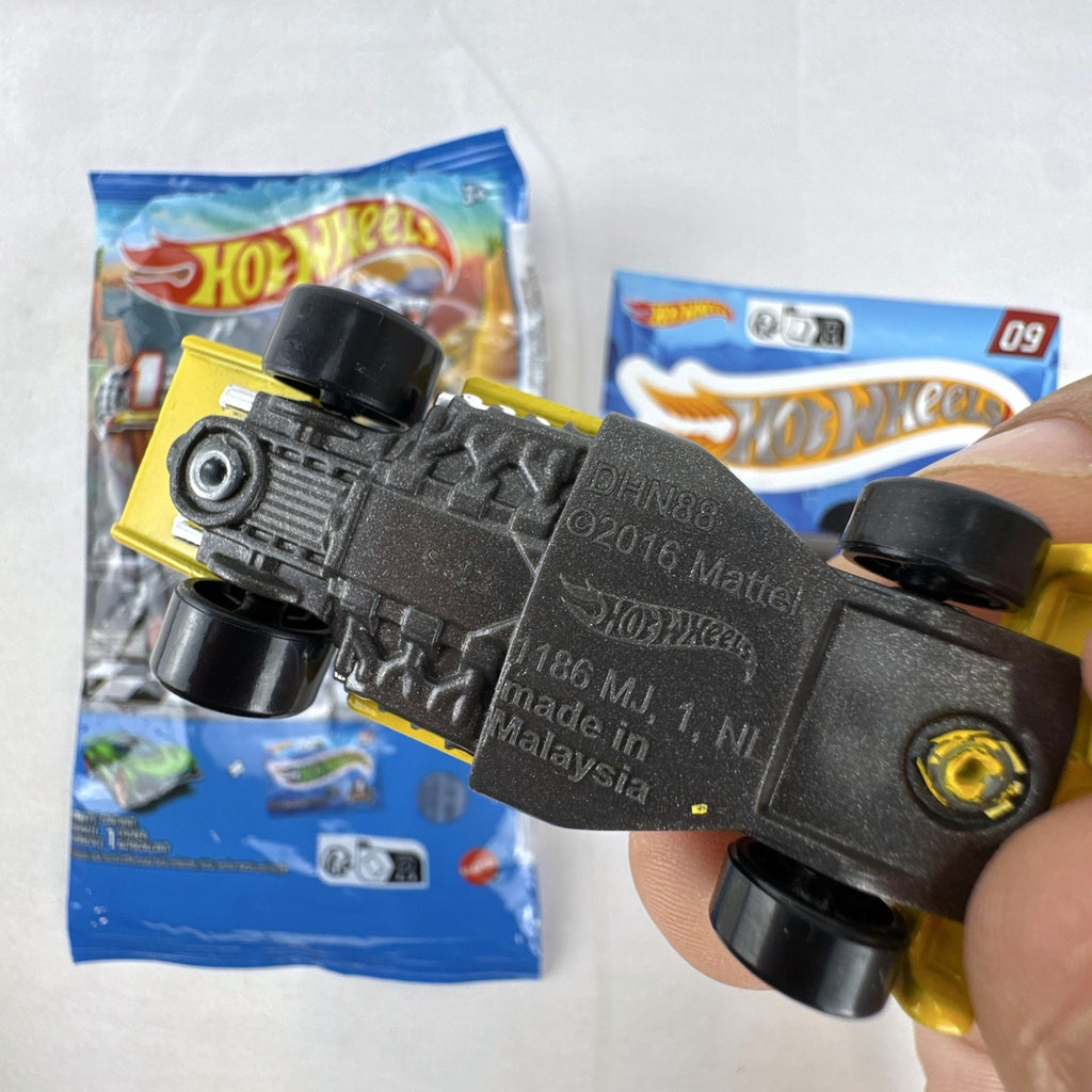 Hot Wheels 1:64 scale Formula Flashback Mystery Models Series 1 yellow diecast racer with sticker card and opened foil pouch