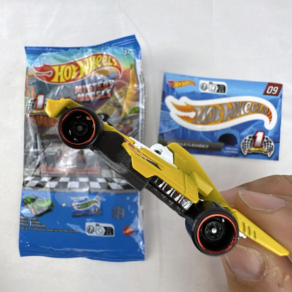 Hot Wheels 1:64 scale Formula Flashback Mystery Models Series 1 yellow diecast racer with sticker card and opened foil pouch