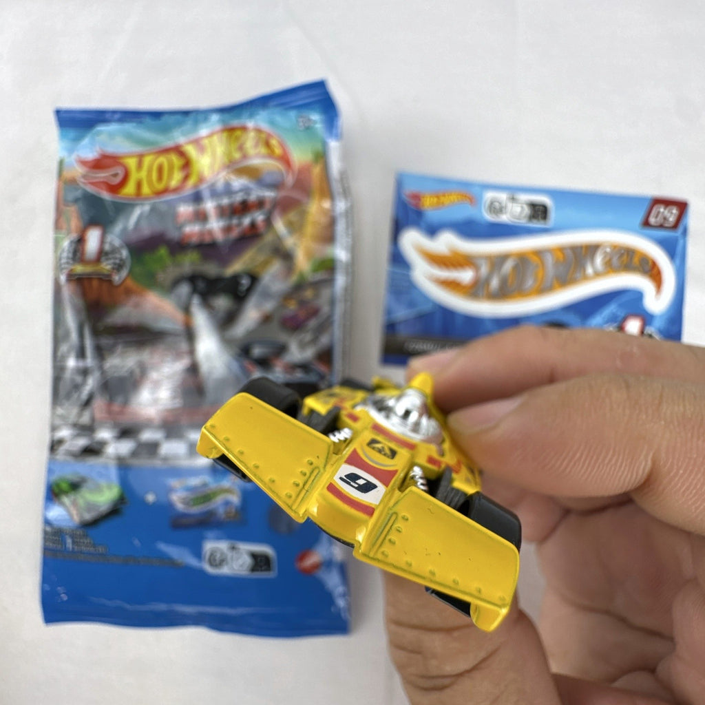 Hot Wheels 1:64 scale Formula Flashback Mystery Models Series 1 yellow diecast racer with sticker card and opened foil pouch