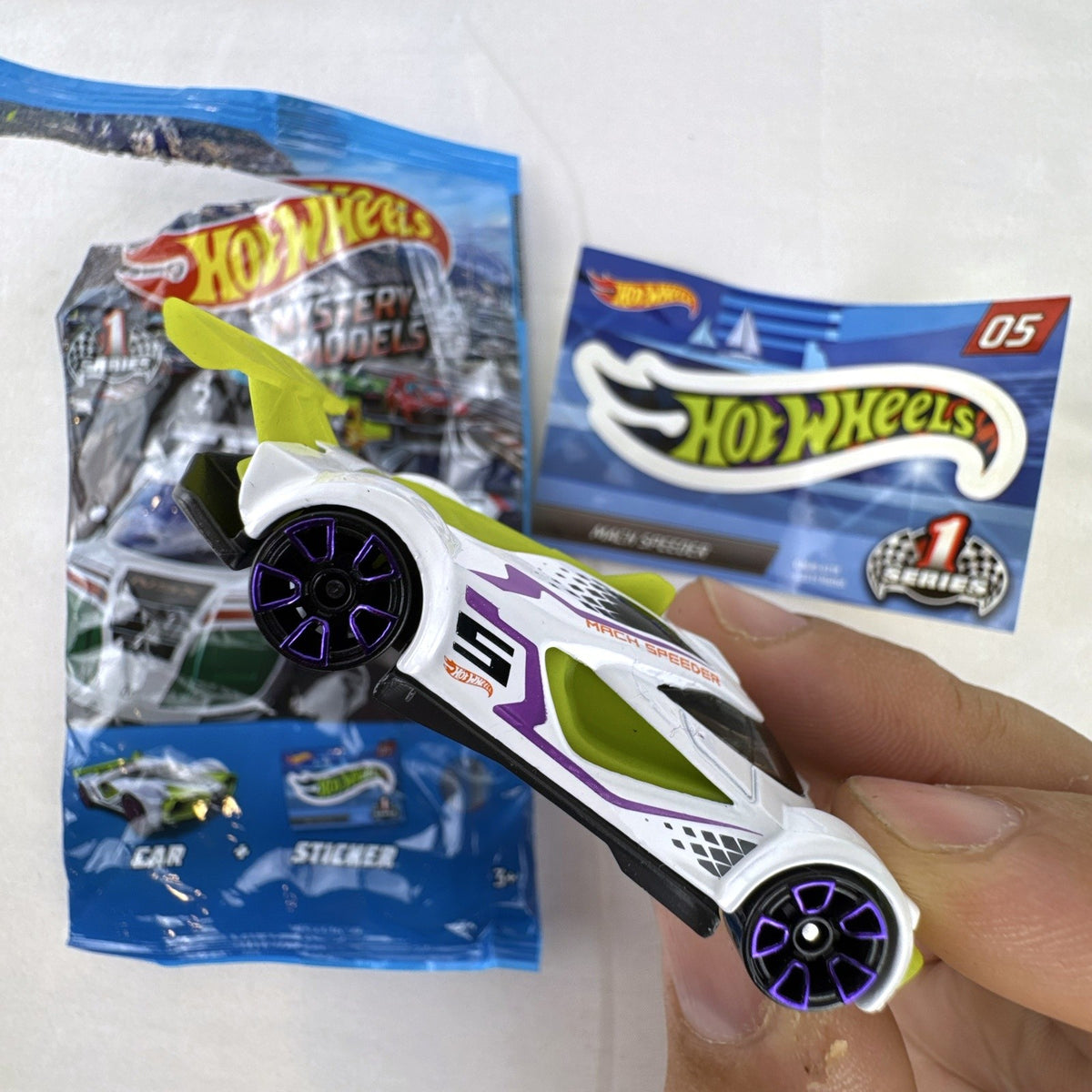 White Hot Wheels Mach Speeder diecast car Mystery Models #05 with purple graphics and lime green accents