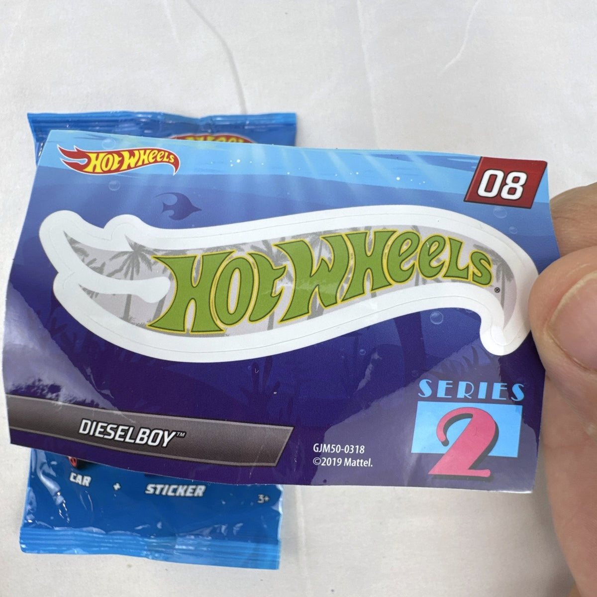 Hot Wheels 1:64 scale Dieselboy diecast car in white and green with original 2020 Mystery Models Series 2 bag and sticker card.