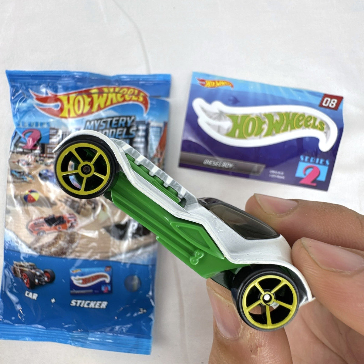 Hot Wheels 1:64 scale Dieselboy diecast car in white and green with original 2020 Mystery Models Series 2 bag and sticker card.