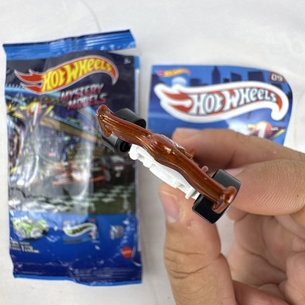 Hot Wheels 1:64 scale F1 Racer diecast car in metallic copper orange with original Mystery Models foil pouch and sticker