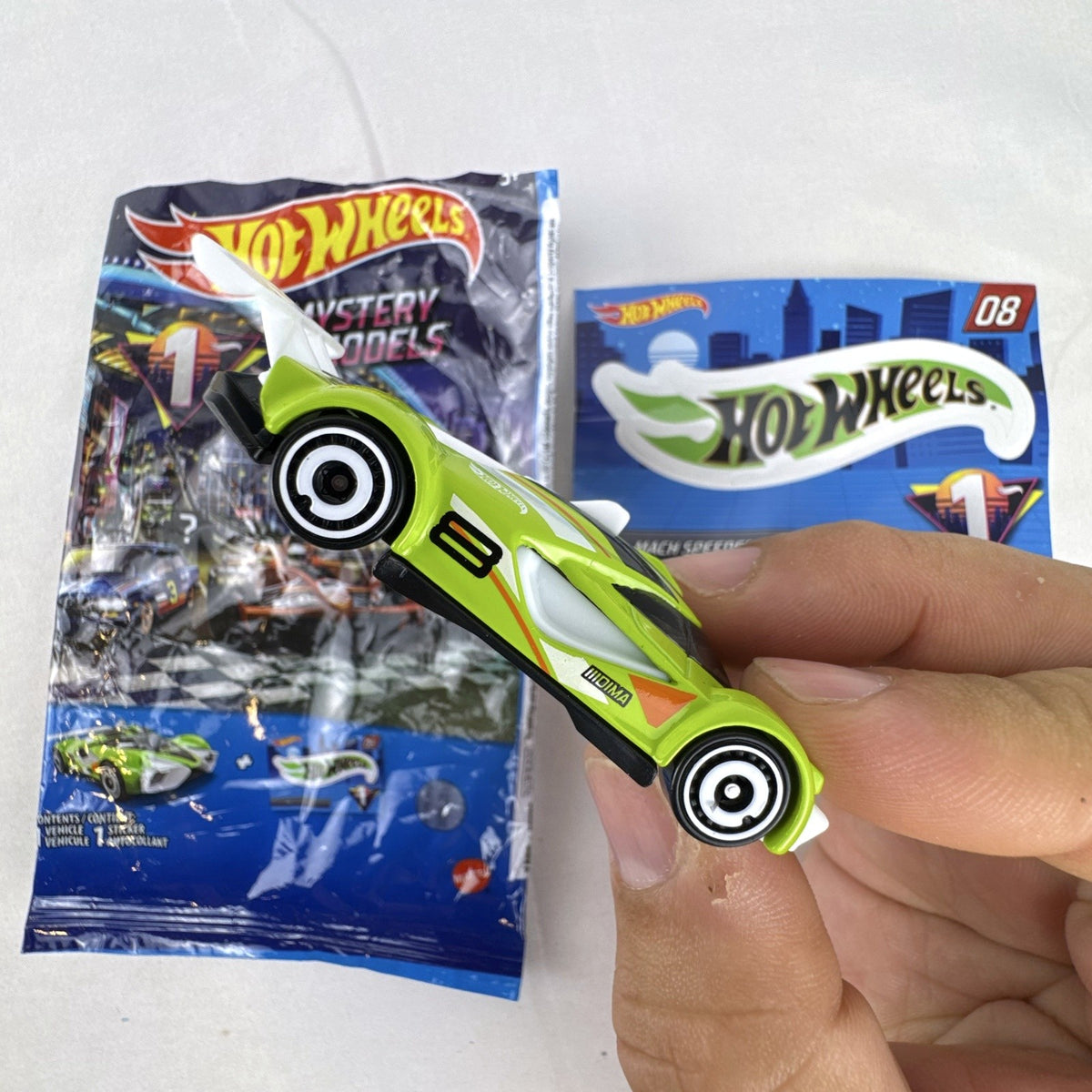 Hot Wheels 2021 Mystery Models Series 1 Mach Speeder #08 diecast car in bright lime green with matching sticker card.
