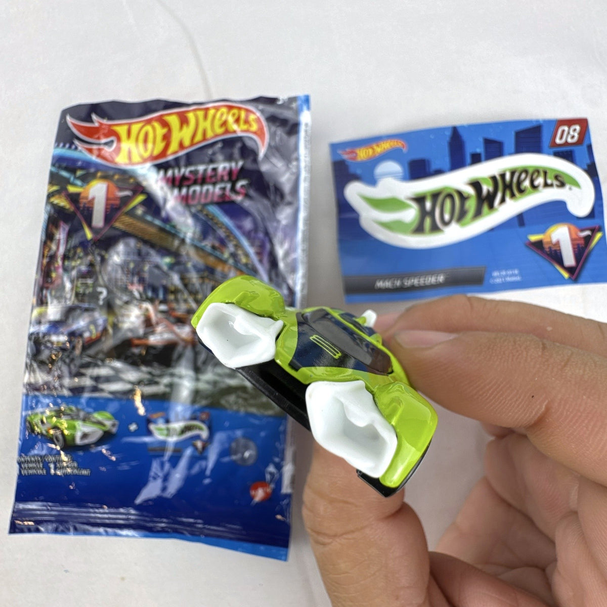 Hot Wheels 2021 Mystery Models Series 1 Mach Speeder #08 diecast car in bright lime green with matching sticker card.