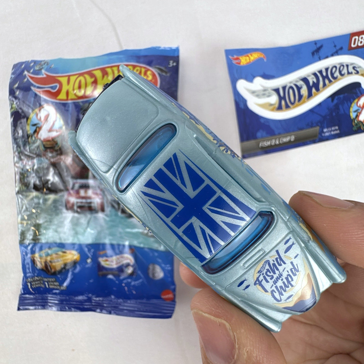 Hot Wheels Fish'd & Chip'd 1:64 scale diecast car in light blue with Union Jack roof graphic and bonus sticker.