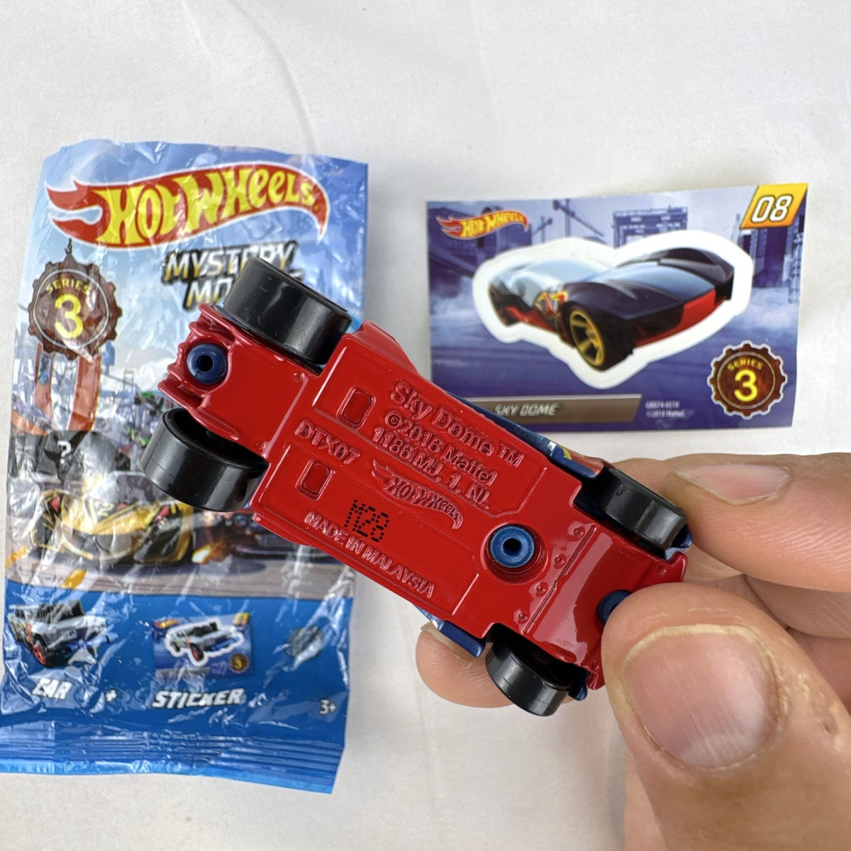Hot Wheels Sky Dome 1:64 scale diecast car in dark blue with original Mystery Models Series 3 sticker card and bag.