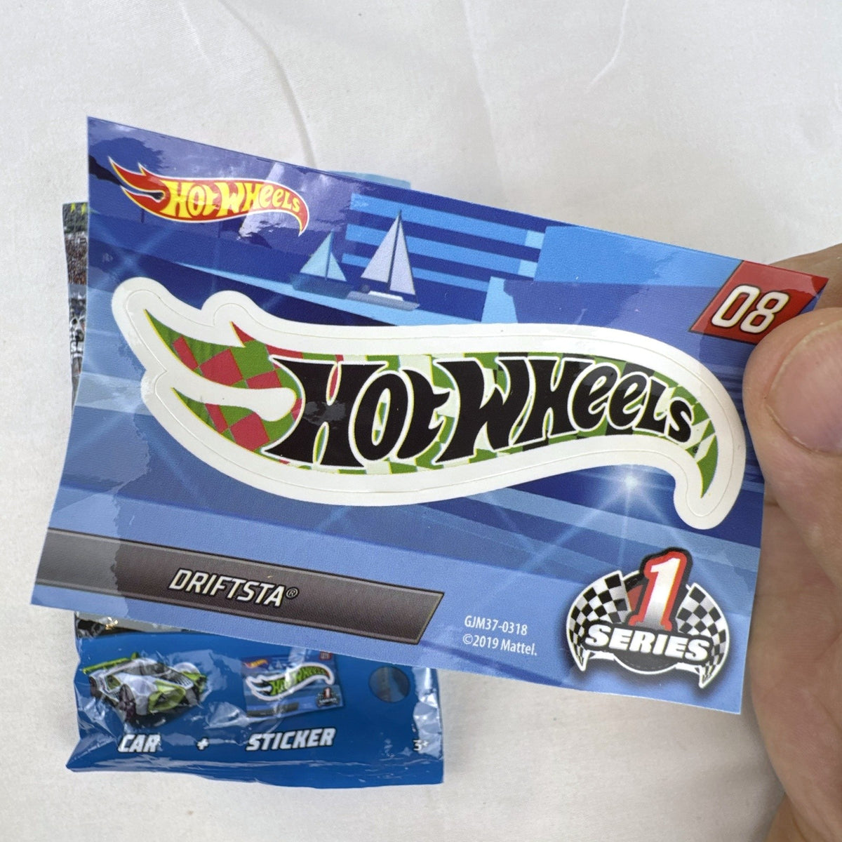 1:64 scale lime green Hot Wheels Driftsta #08 diecast car with Mystery Models sticker card and foil pack.