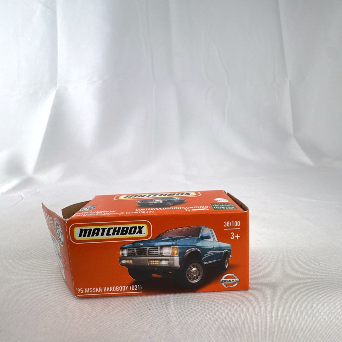 Matchbox 1:64 scale 1995 Nissan Hardbody D21 diecast pickup truck in metallic teal blue with original Power Grabs box