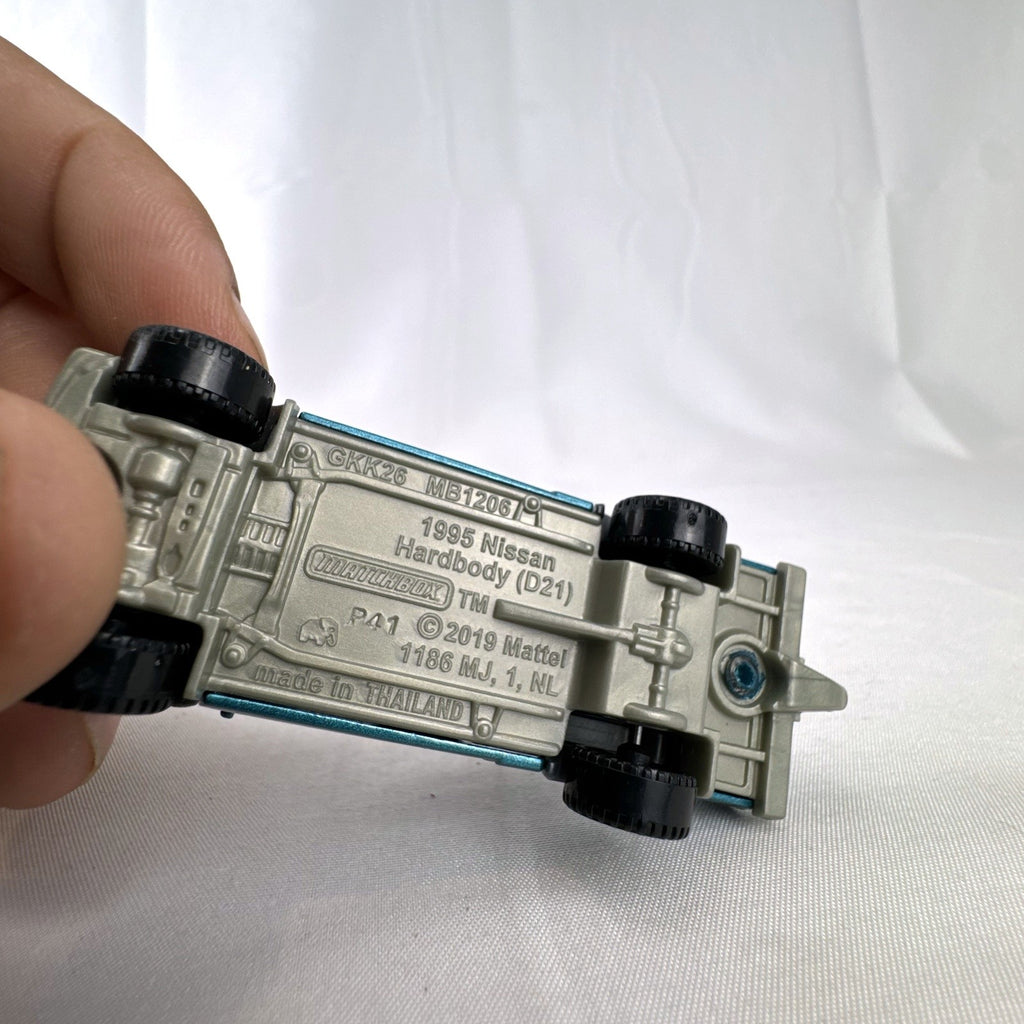 Matchbox 1:64 scale 1995 Nissan Hardbody D21 diecast pickup truck in metallic teal blue with original Power Grabs box