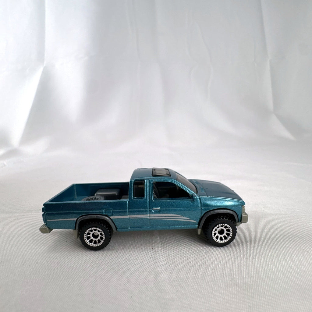 Matchbox 1:64 scale 1995 Nissan Hardbody D21 diecast pickup truck in metallic teal blue with original Power Grabs box