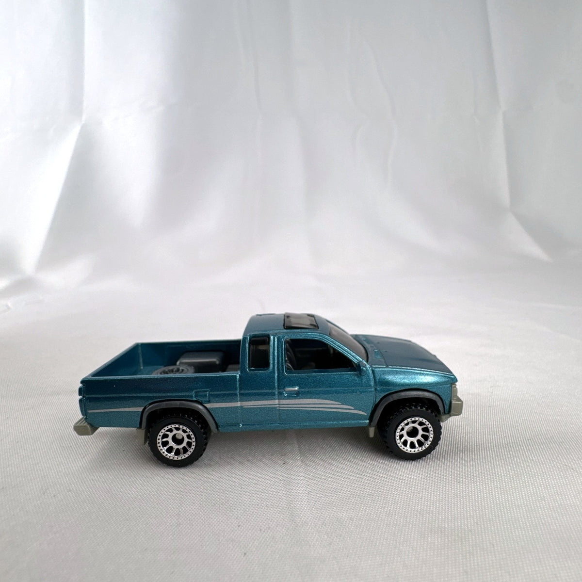 Matchbox 1:64 scale 1995 Nissan Hardbody D21 diecast pickup truck in metallic teal blue with original Power Grabs box