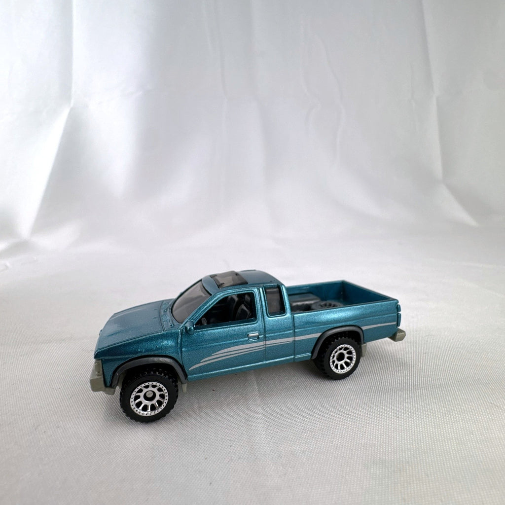 Matchbox 1:64 scale 1995 Nissan Hardbody D21 diecast pickup truck in metallic teal blue with original Power Grabs box