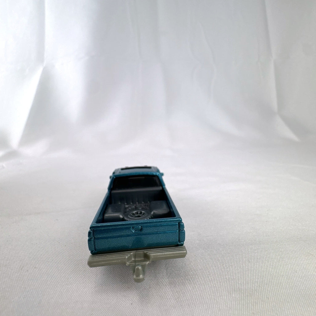 Matchbox 1:64 scale 1995 Nissan Hardbody D21 diecast pickup truck in metallic teal blue with original Power Grabs box