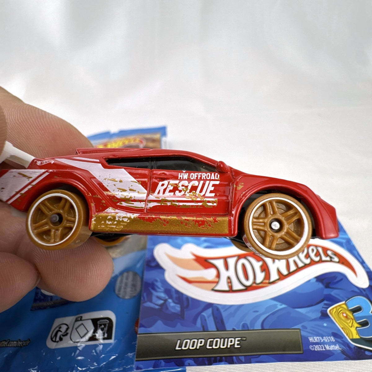 Hot Wheels Loop Coupe 1:64 scale red off-road rescue diecast car with mystery bag and sticker card.