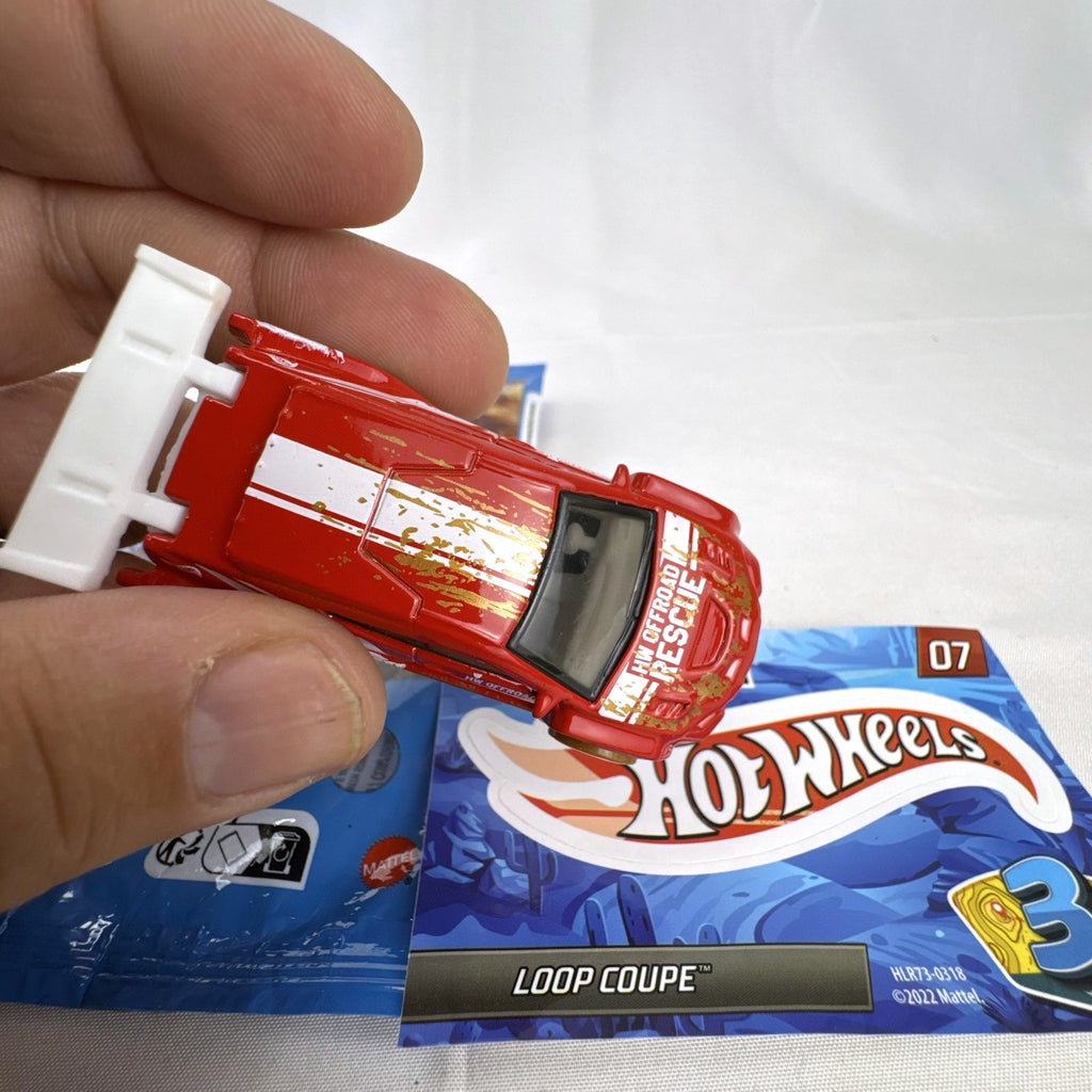 Hot Wheels Loop Coupe 1:64 scale red off-road rescue diecast car with mystery bag and sticker card.