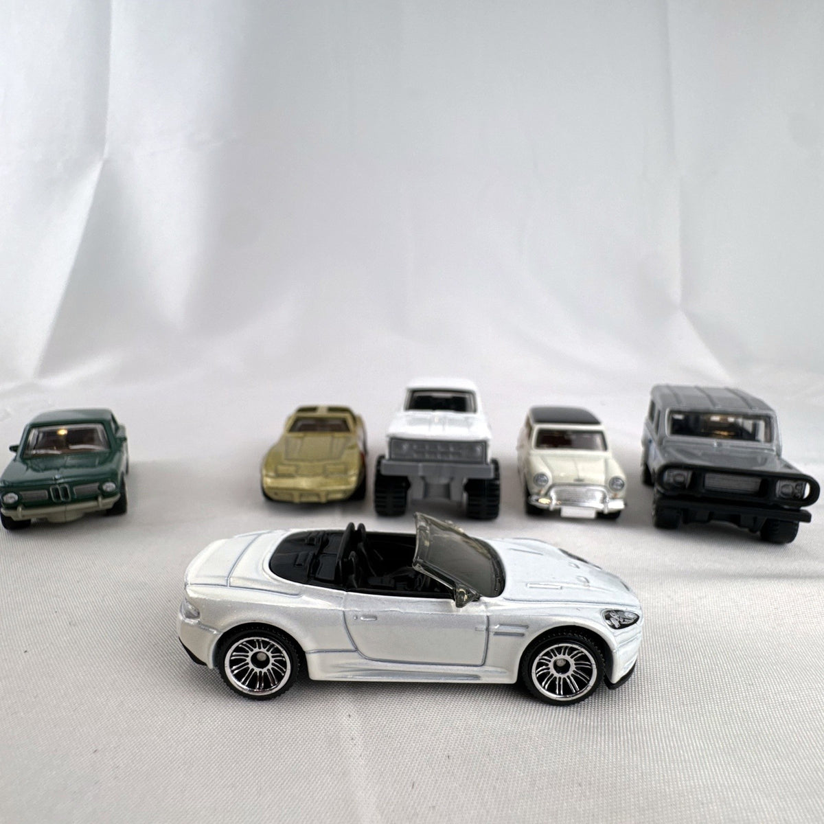 Set of six loose Matchbox diecast vehicles including BMW 2002, Corvette, Mini Cooper, Aston Martin, Dodge, and Land Rover