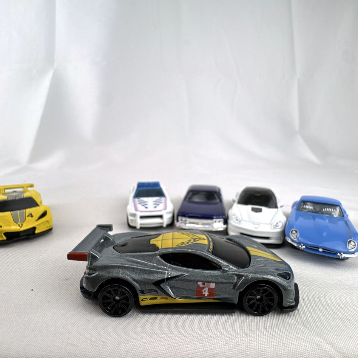 Set of 6 loose 1:64 scale Hot Wheels and Matchbox diecast cars including Corvette C8.R, Mustang, Caprice, and Jaguar E-Type